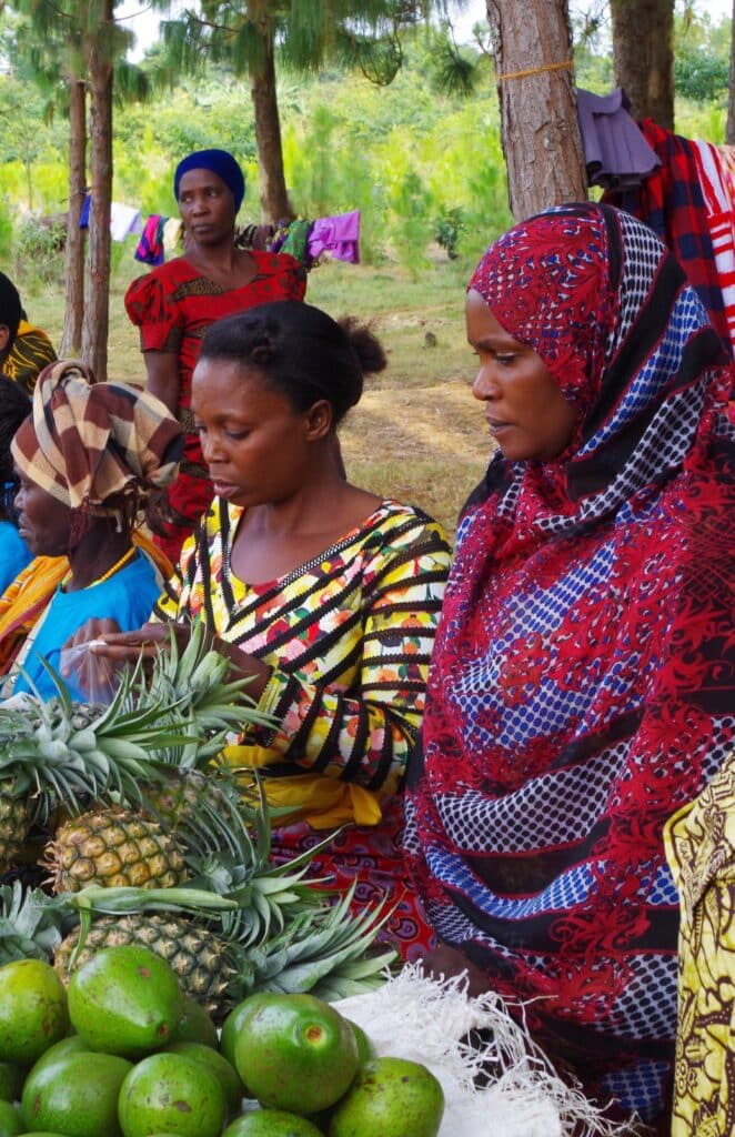 Women working on a table with various fruit.