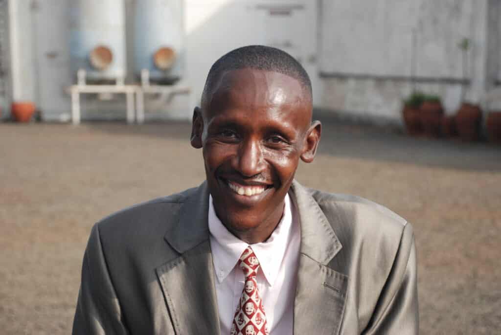 Smiling man wearing a suit outside.