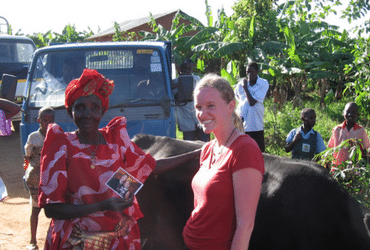 Gaudensia Nakafeero standing beside a woman with a black cow behind them.