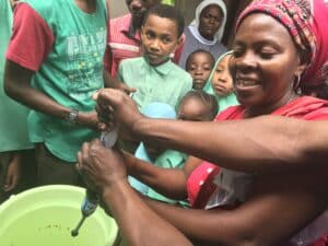 Teacher and her students filling a bucket with filtered water.