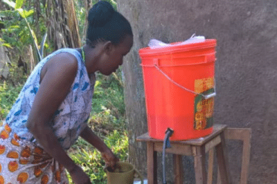 Woman and child filling blue bucket with filtered water.