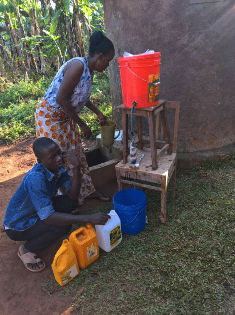 Woman and child filling blue bucket with filtered water.