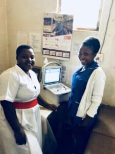 A pregnant woman and her midwife beside an ultrasound machine.