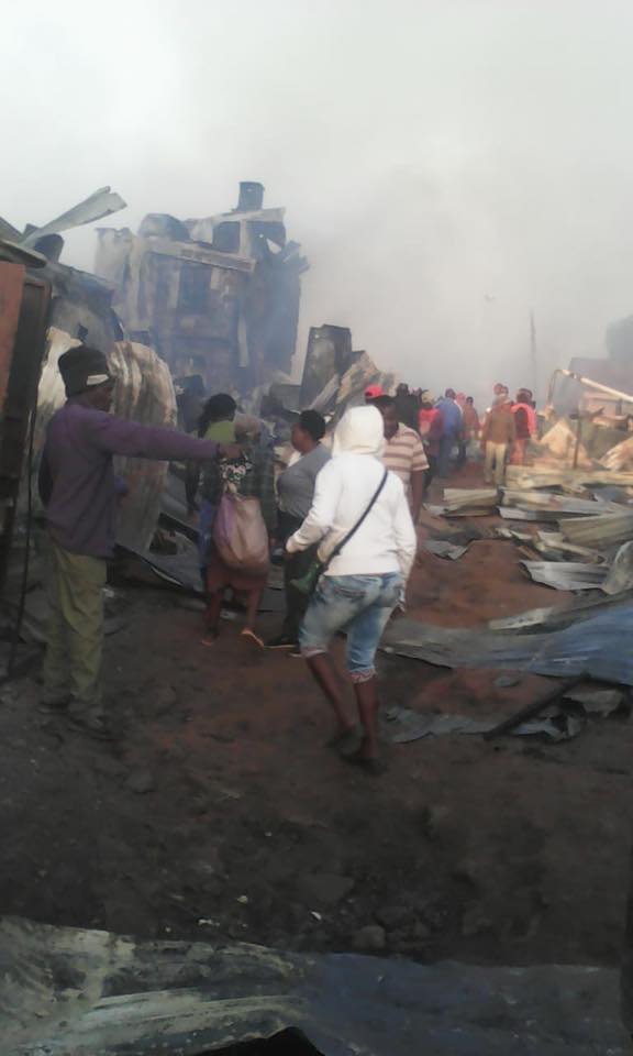 People walking through the aftermath of a devastating fire.