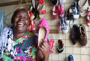 Margaret Wanjiru laughing as she holds a bright pink shoe.