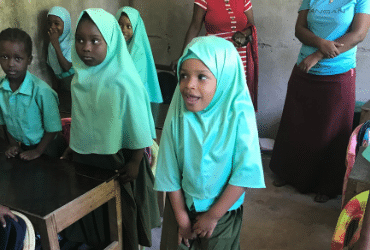 Young children standing in a classroom.