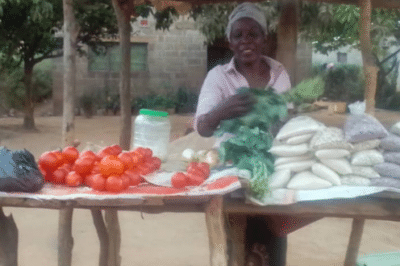 Woman standing outside behind a table of produce.