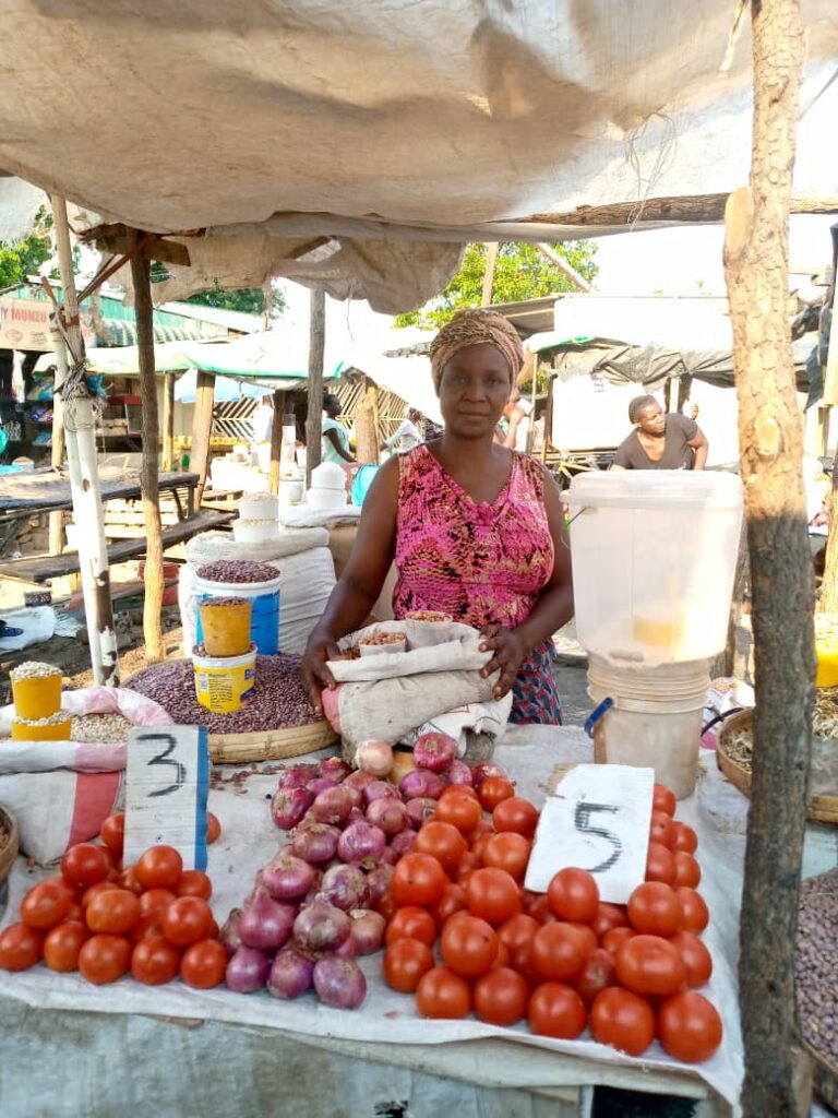 Woman at fruit stand in outdoor market.