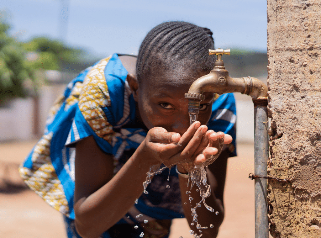 Girl looking at camera and drinking from water fountain.