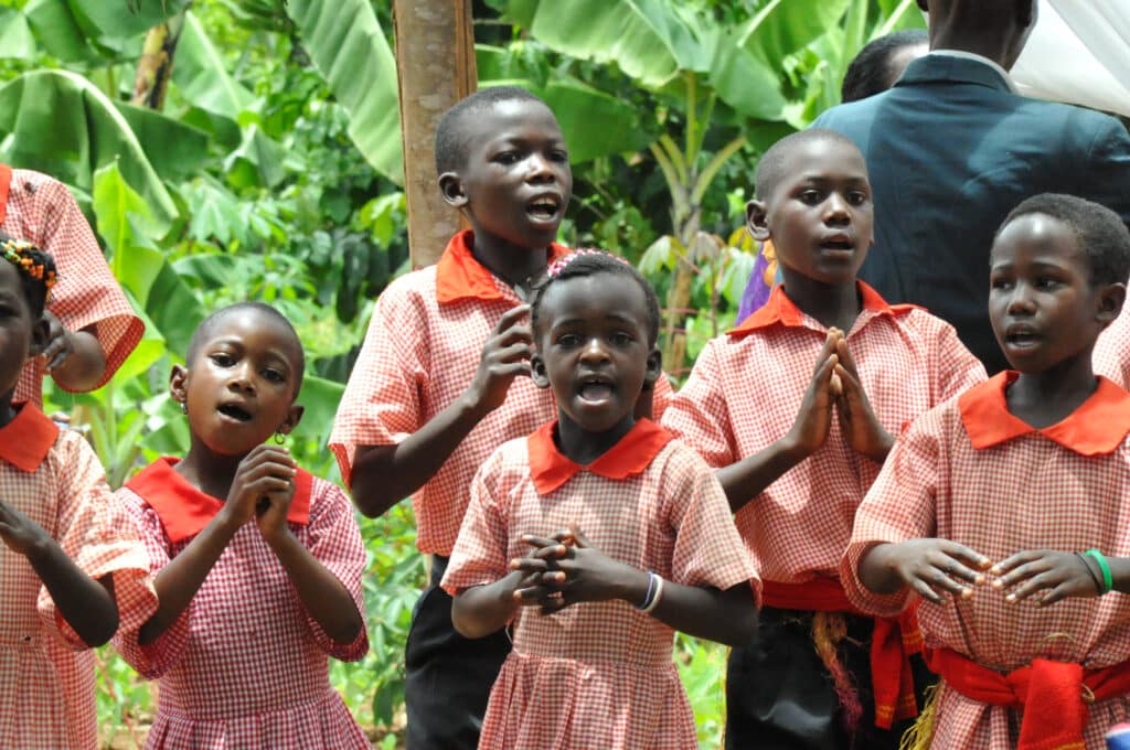 A group of young children singing outside.