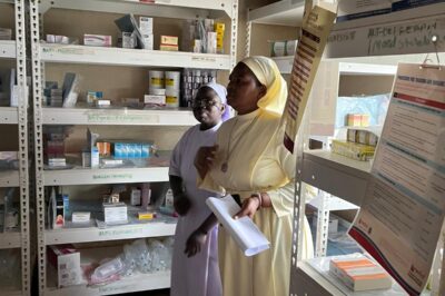 Two midwives standing in a medical supply room.
