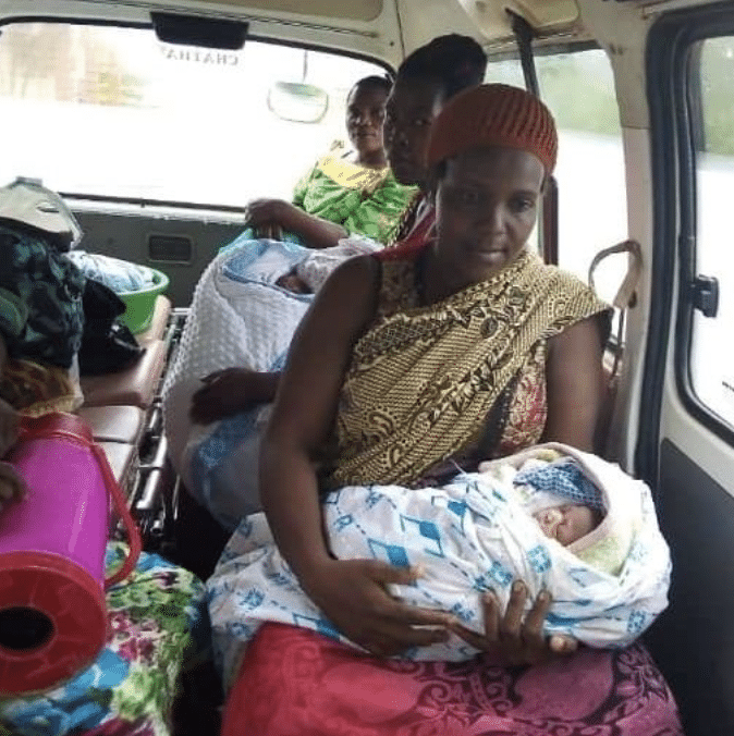Three women riding in a van while they hold their babies.