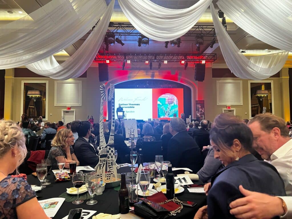 Group of people sitting at round tables watching a video screen at the 17th African Gala.