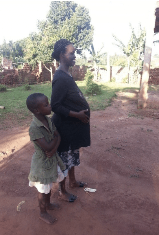 Esther Namwanje standing outside with her child.