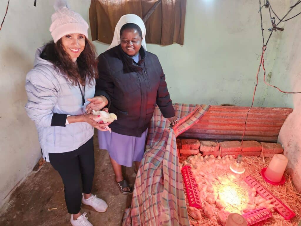 Two women holding chicks and smiling.