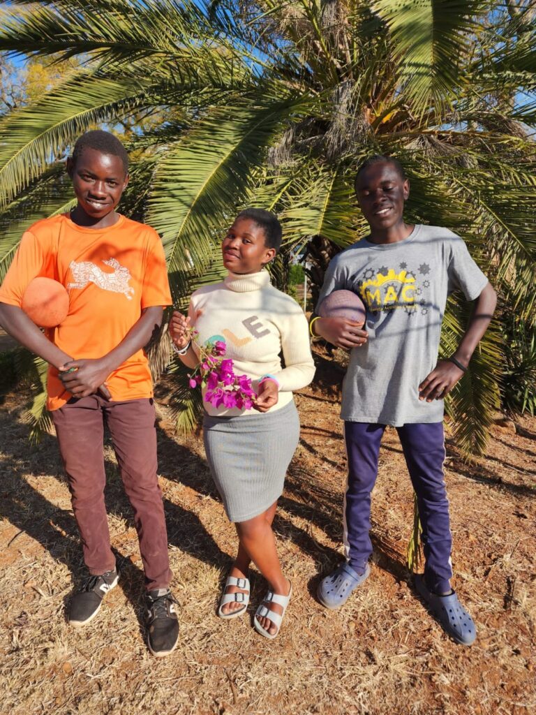 Three young people smiling outdoors.