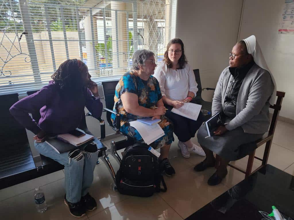 Four women talking together indoors.