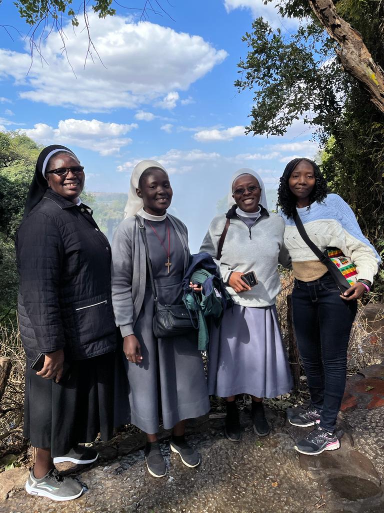 Four women smiling at the camera at a scenic overlook.