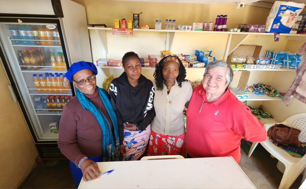 Four women in a small shop where grocery items are being sold.