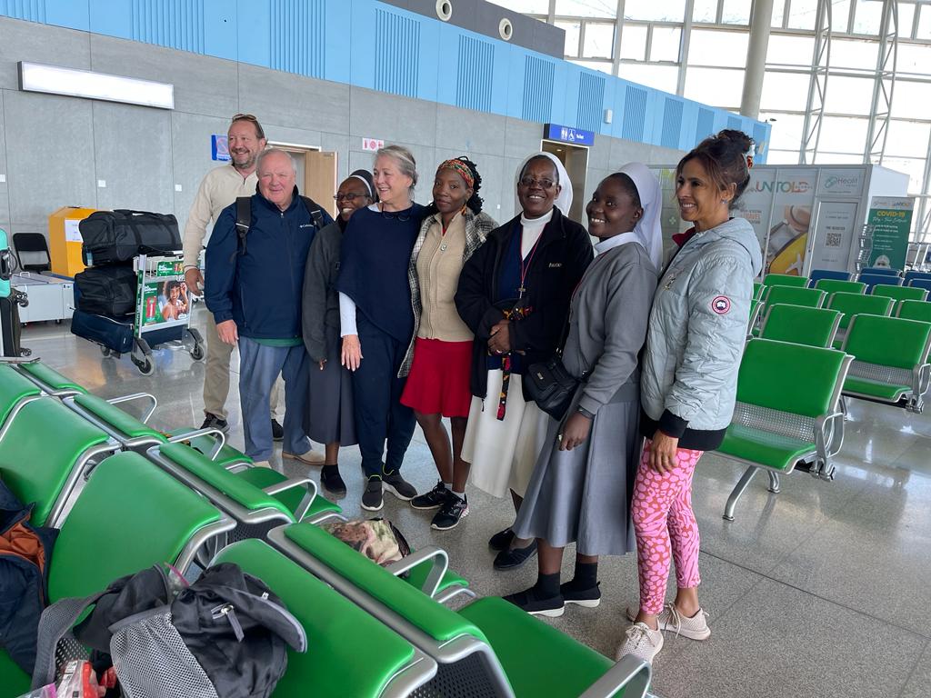 A group of people at the airport smiling at the camera.