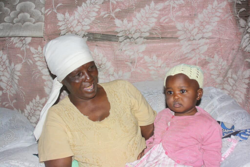 Jane in Mathare holding her grandchild on her lap.