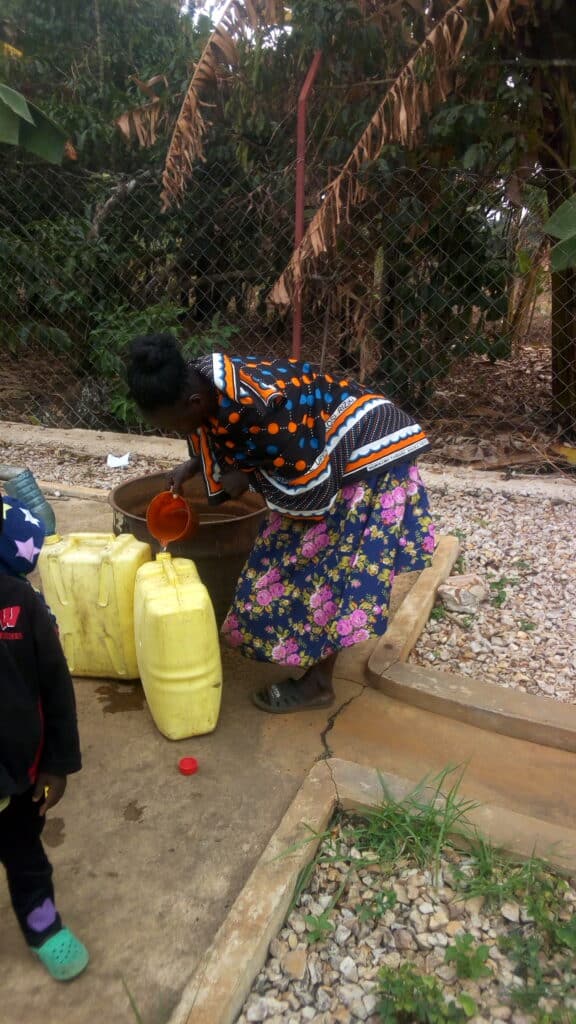 People using a community water spigot.