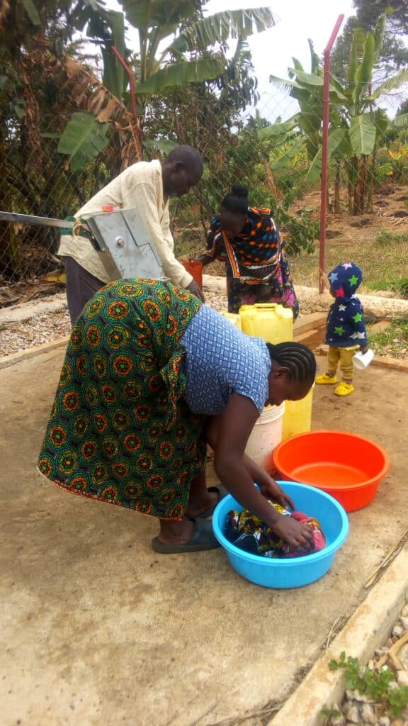 People using a community water spigot.