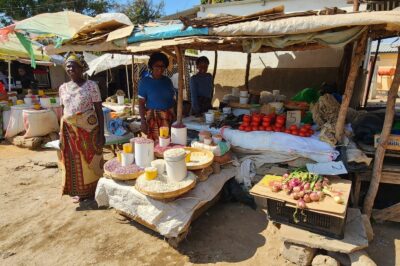 Three women tending a small shop in an open air marketplace in a rural village in Africa.