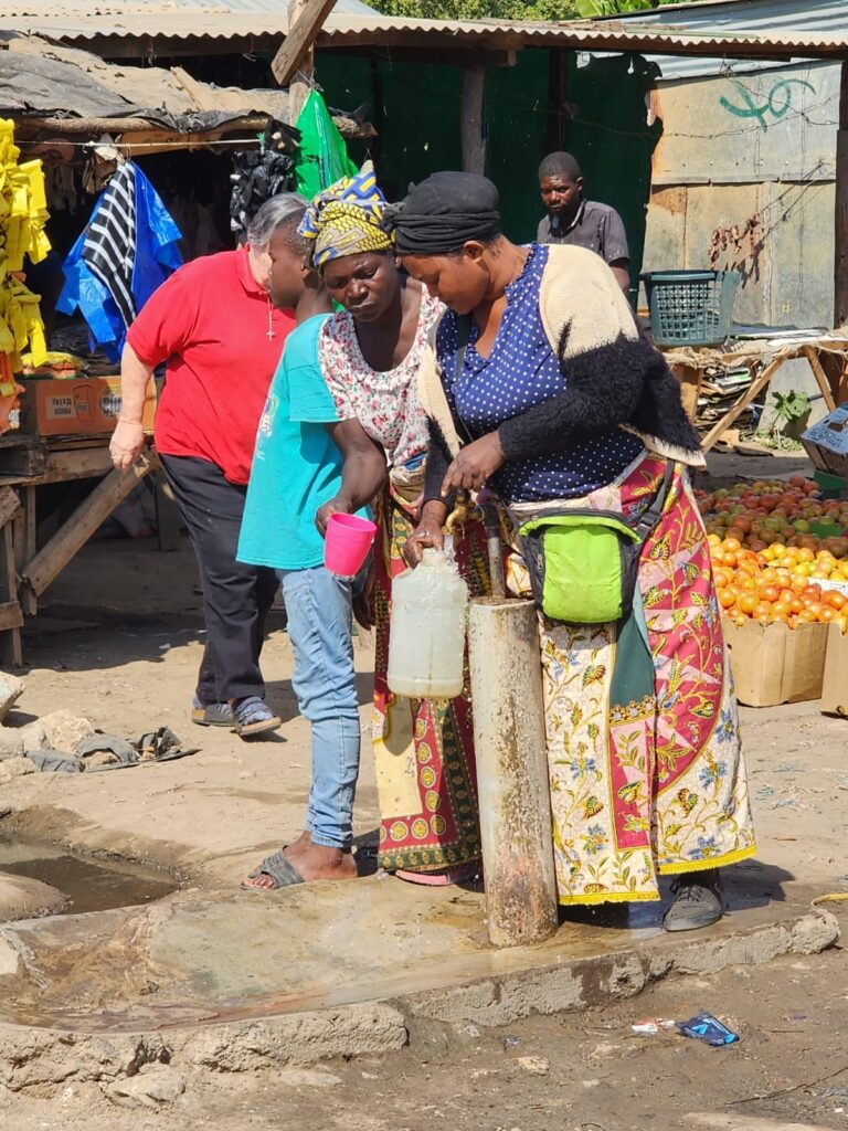 Two women getting water from a community spigot.