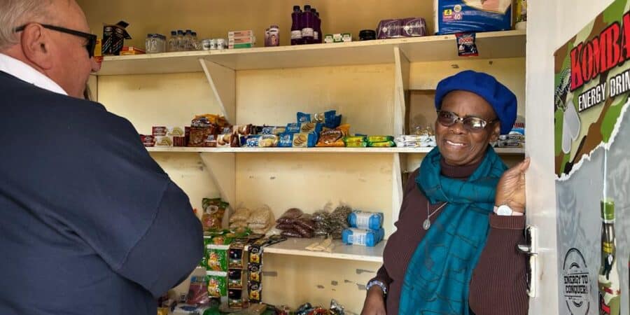 A woman operating a small shop with grocery items.