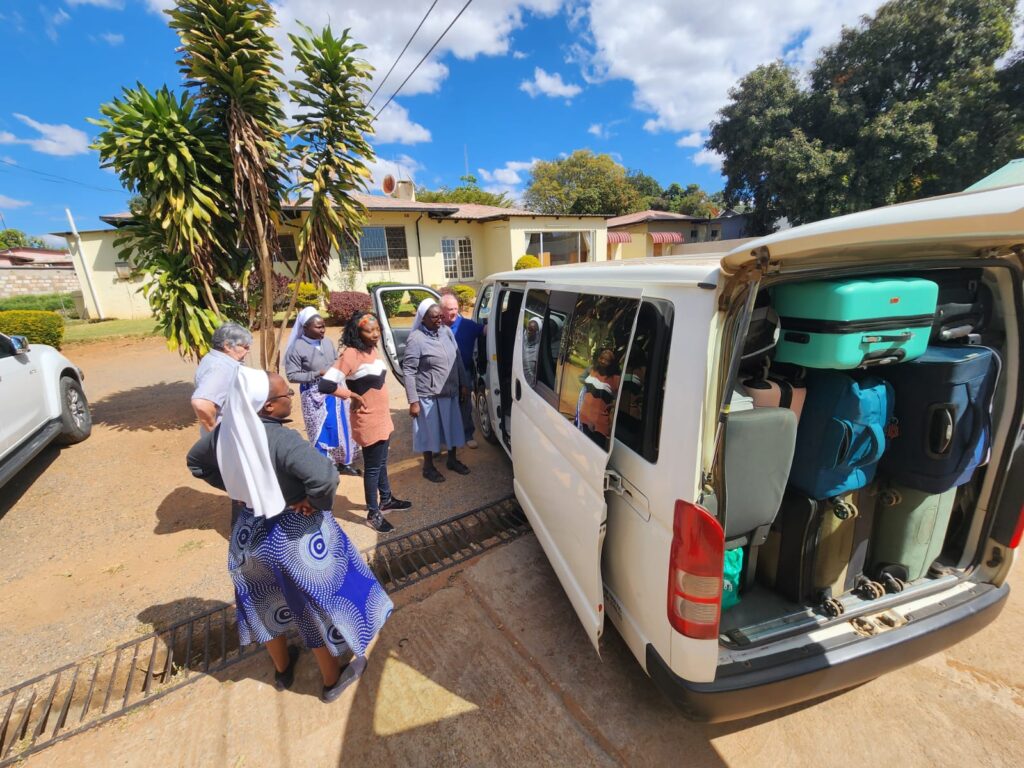 A group of people gathered around a van filled with suit cases.